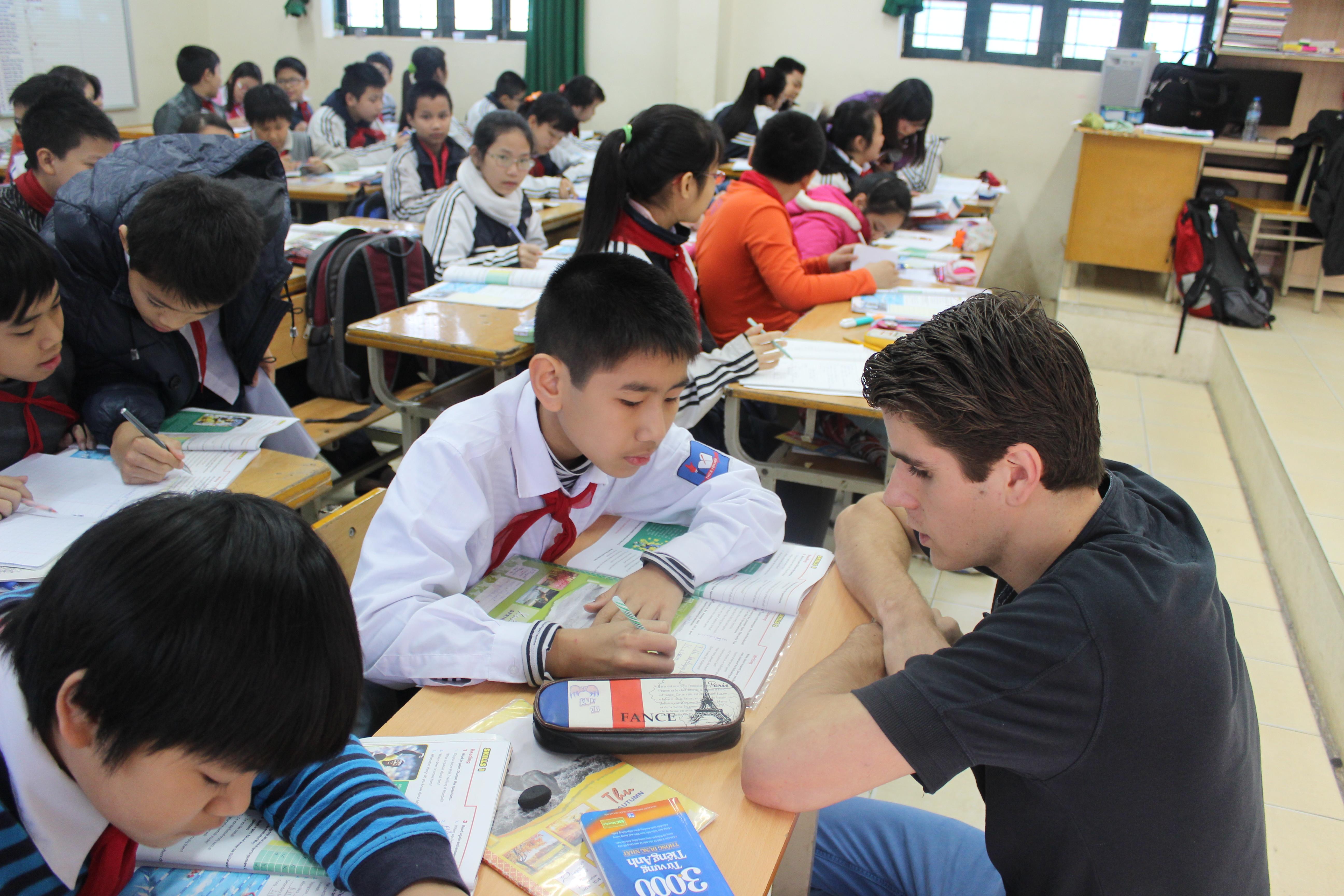 A Projects Abroad Teaching volunteer in Vietnam helps a students with his classwork A volunteer helps his students in class during his teaching work experience in Vitenam